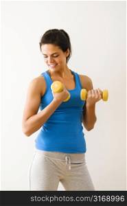 Woman lifting hand weights and smiling.
