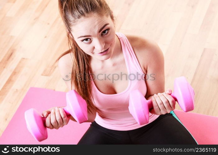 Woman lifting two dumbbells. Young girl exercising in gym. Health workout fitness concept. . Woman lifting two dumbbells.