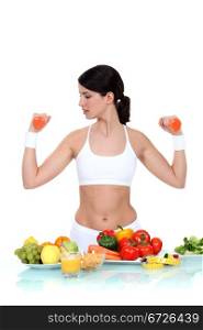 Woman lifting weights surrounded by vegetables
