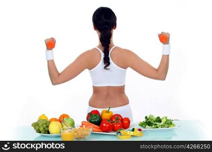 Woman lifting weights with back turned to vegetables