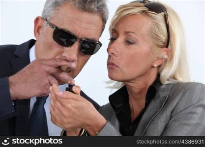 woman lighting her man&rsquo;s cigar