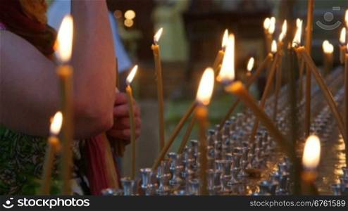 Woman lighting prayer candle in Christian Orthodox Church