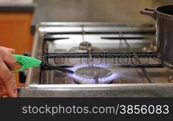 woman lights gas and puts pan on gas cooker.