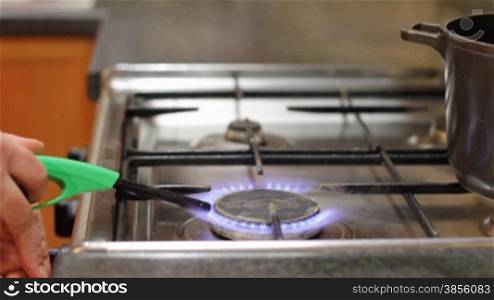 woman lights gas and puts pan on gas cooker.