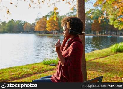 Woman listening music in the autumn park at sunset with headphones