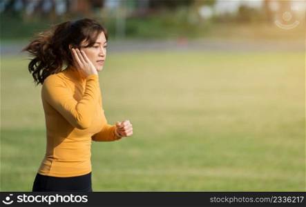 woman listening music on earphones while running in the park