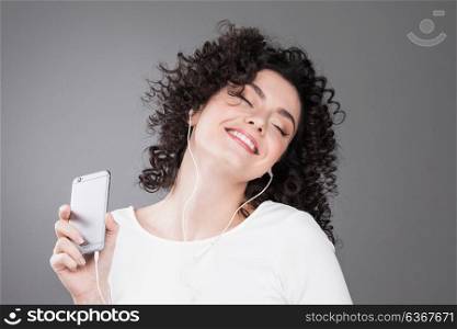 Woman listening music. Portrait of happy woman listening music in headphones on gray background with copy space