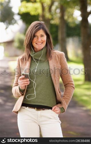 Woman Listening To MP3 Whilst Walking In Autumn Park