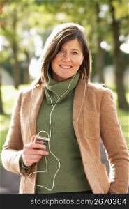 Woman Listening To MP3 Whilst Walking In Autumn Park