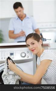 woman loading dirty clothes in washing machine