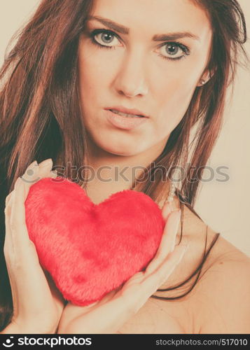 Woman long hair young female holding red heart love symbol studio shot on bright. Valentines day happiness concept. Filtered photo. Woman holds red heart love symbol