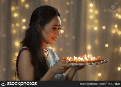 Woman looking at a plate decorated with diyas 