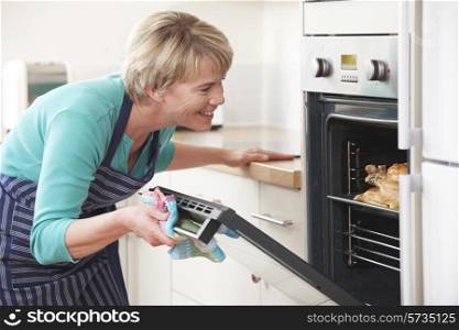 Woman Looking At Chicken Roasting In Oven