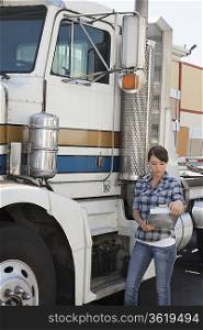 Woman looking at clipboard while standing by flatbed truck