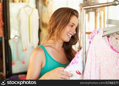 Woman Looking At Clothes On Rail In Store