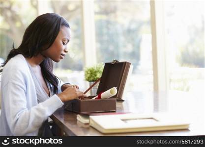 Woman Looking At Document In Keepsake Box On Desk