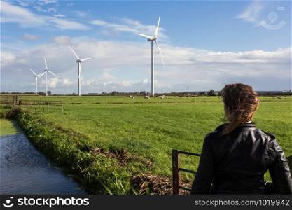 Woman looking at dutch landscape, windmills and cows in the distance with blue sky ,meadow. Woman looking at dutch landscape, windmills and cows in the distance with blue sky