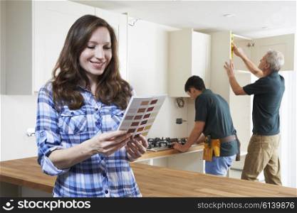Woman Looking At Paint Chart In New Kitchen
