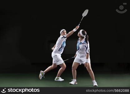 Woman looking at partner holding badminton over black background