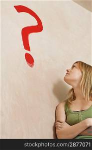Woman Looking at Question Mark on Wall