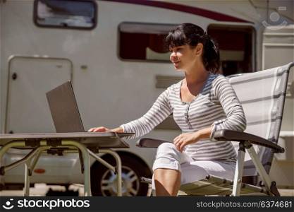Woman looking at the laptop near the camping . Caravan car Vacation. Family vacation travel, holiday trip in motorhome RV. Wi-fi connection information communication technology.