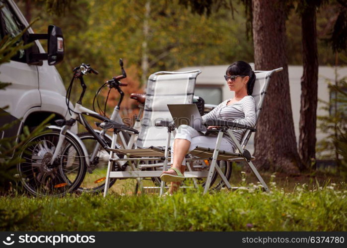 Woman looking at the laptop near the camping . Caravan car Vacation. Family vacation travel, holiday trip in motorhome RV. Wi-fi connection information communication technology.