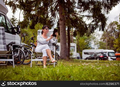 Woman looking at the tablet near the camping . Caravan car Vacation. Family vacation travel, holiday trip in motorhome RV. Wi-fi connection information communication technology.