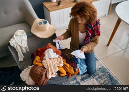 Woman looking at too much clothes in travel bag. Overwhelmed girl choosing apparel for vacation trip. Overwhelmed woman choosing apparel for vacation trip