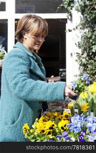Woman looking at various pots with violets outside a florist shop