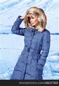Woman looking away, wearing warm stylish blue coat with furry hood, wintertime fashion, cold weather, winter holidays concept