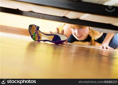 woman looking for her shoe under the bed