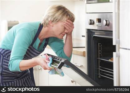 Woman Looking In Oven And Covering Eyes Over Disasterous Meal