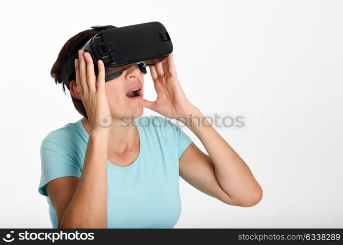 Woman looking in VR glasses and gesturing with his hands. Beautiful surprised female wearing virtual reality goggles watching movies or playing video games, isolated on white background.