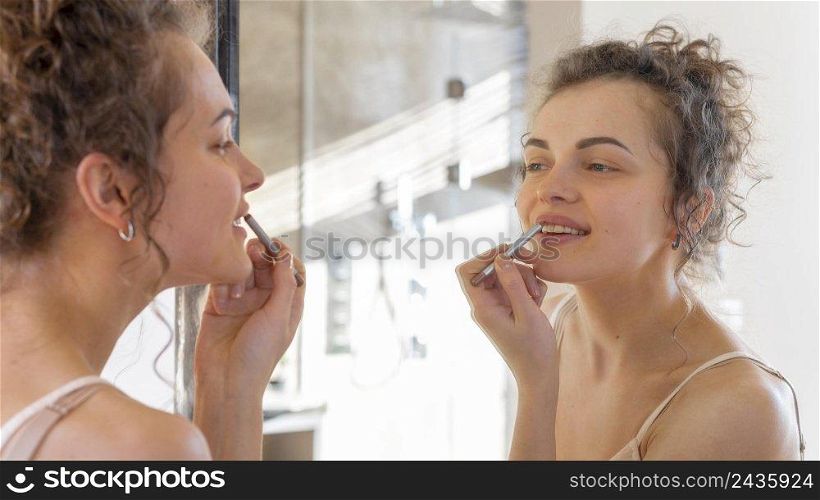 woman looking mirror applying lipstick 2
