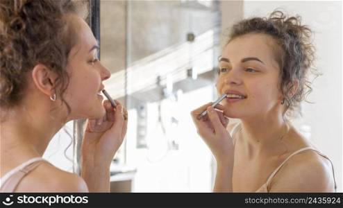woman looking mirror applying lipstick 2