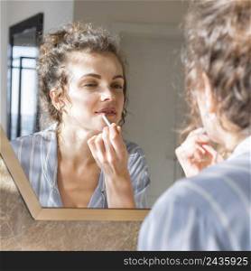 woman looking mirror applying lipstick 3