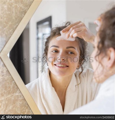 woman looking mirror doing face massage