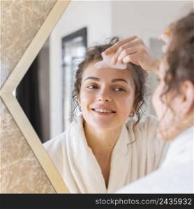 woman looking mirror doing face massage