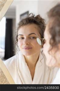 woman looking mirror doing face massage 3