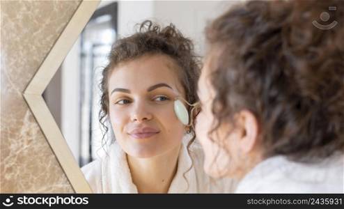 woman looking mirror doing face massage 4