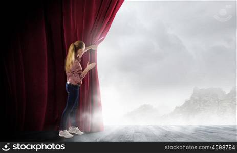 Woman looking out from curtain. Young woman in casual opening red curtain and looking at clear sky