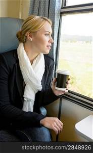 Woman looking out the train window pensive commuter coffee trip