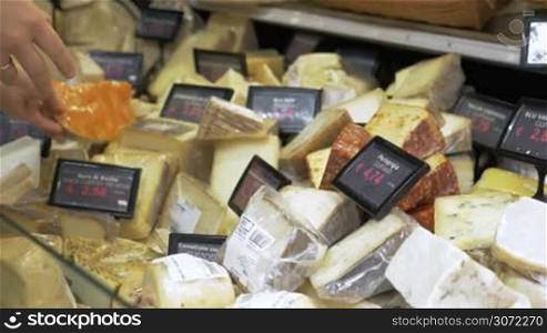 Woman looking over different types of cheeses in the shop. Variety of choice in kinds and prices