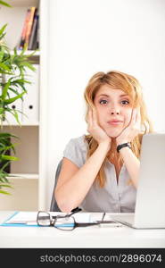 Woman looking surprised with laptop sitting at the table in the office