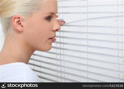 Woman looking through blinds