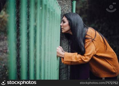 Woman looking through the metal fence in the forest