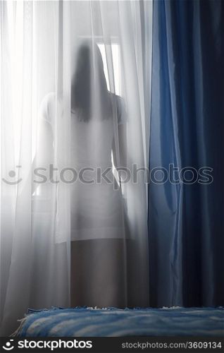 Woman looking through window, back view