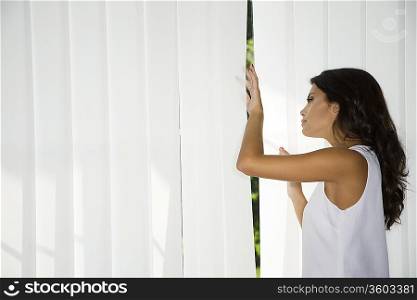 Woman looking trough curtains