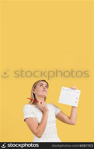 woman looking up holding menstruation calendar with copy space
