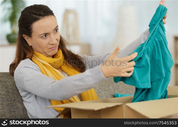woman looking with disdain at a top delivered by courrier